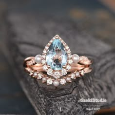 an aqua and white diamond ring on top of a rock