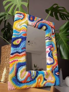 a multicolored mirror sitting on top of a table next to a potted plant