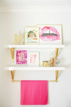 two white shelves with pink towels and pictures on them, one is hanging from the wall