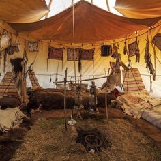 an inside view of a tent with several items hanging from it's ceiling and some hay on the ground