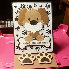 a birthday card with a dog and paw prints on it, sitting on a pink tray