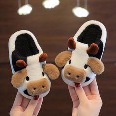 someone is holding up two slippers with a cow on it's face and nose