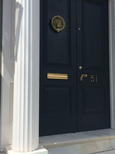 a black front door with two white pillars and a gold knocker on the side