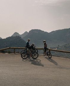 three people riding bikes on top of a mountain