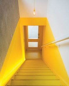 the stairs lead up to an open door with bright yellow light coming from it's side