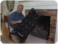 a man is holding two pieces of luggage in front of a fire place with a fireplace