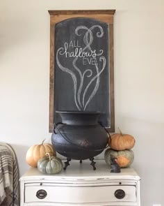 a chalkboard that says all hallow's eve on top of a chest of drawers