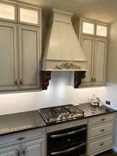 a stove top oven sitting inside of a kitchen next to white cupboards and drawers