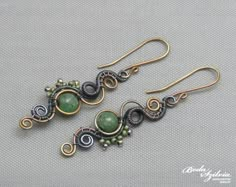 two earrings with green beads and wire work on the earwires, sitting on a gray surface