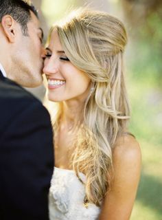 a bride and groom kissing each other outside