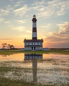 a light house sitting on top of a lush green field next to a body of water