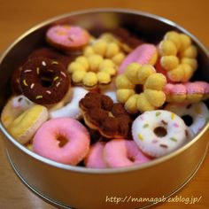 a tin filled with lots of different types of donuts on top of a wooden table