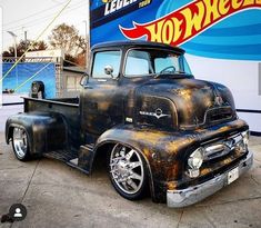 an old truck parked in front of a hot wheels sign