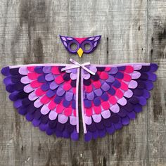 an owl made out of purple and pink paper on top of a wooden fence with scissors