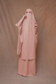 Introducing Pink Moira Prayer Umrah Gown with Niqab Feature from Annah Hariri. This beautiful gown is made from high-quality Nada abaya fabric and features super light, stretchy jersey sleeves for ultimate comfort. The elasticated waistband and full skirt ensure a flattering and secure fit, while the khimar can be tied at the back of the head for added coverage.But the best part? This gown can also be transformed into a niqaab with just a few simple stitches. So whether you're performing Umrah, Modest Activewear, Full Coverage Swimsuit, Modest Maxi Dress, Modest Maxi, Abaya Dress, Niqab, Gowns Online, Gowns With Sleeves, Full Skirt