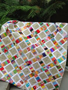 a patchwork quilt is displayed on a bench