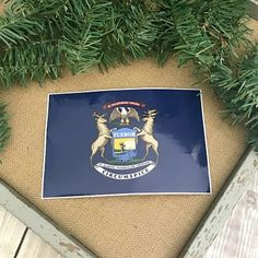 the flag of massachusetts is hanging on a door mat in front of an evergreen tree