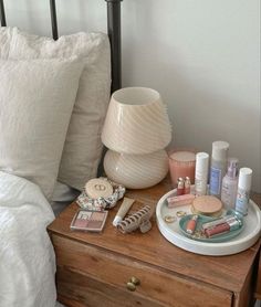 a wooden dresser topped with lots of personal care items next to a white lamp shade