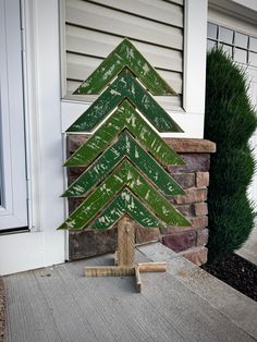 a wooden christmas tree sitting in front of a house