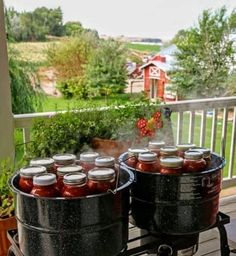 two large black pots filled with food on top of a wooden table next to an outdoor grill