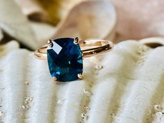 a blue stone ring sitting on top of a white piece of paper with shells in the background