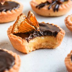 chocolate and orange pies are sitting on a baking sheet with other pastries in the background