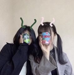 two women are holding up coffee cups with ant horns on their heads, and one woman is covering her eyes