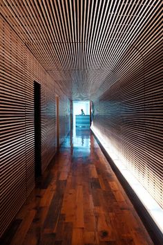 an empty hallway with wood flooring and wooden slats on the wall behind it