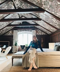 a woman sitting on top of a bed in a bedroom