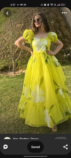 a woman in a yellow dress is standing on the grass with her hands on her hips