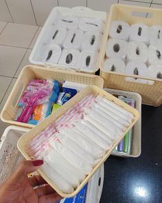 two baskets filled with white toilet paper and toothbrushes on top of a counter