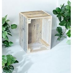 a wooden box sitting next to some green plants