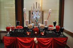 the table is set up with black and red decorations for an elegant dinner or party