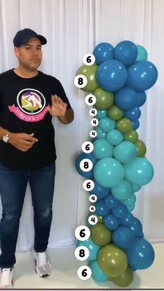 a man standing in front of a number line made out of balloons and numbers on the wall