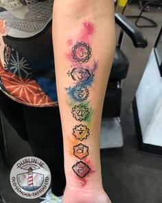 a person with a tattoo on their arm that has seven chakras painted on it