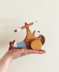 a hand holding a small wooden toy airplane