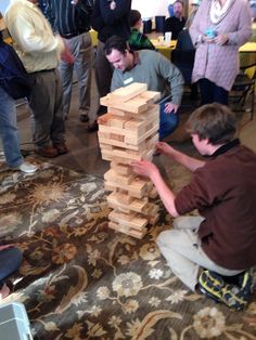 a group of people standing around a pile of wooden blocks on top of a rug