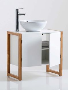 a white sink sitting next to a wooden stand with a bowl on top of it