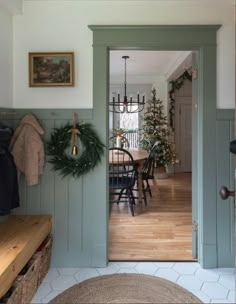 an open door leading to a dining room with christmas wreaths on the wall and table