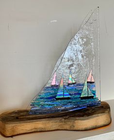 three sailboats are shown on a piece of wood