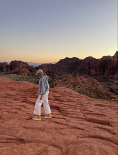 a man standing on top of a red rock covered hillside