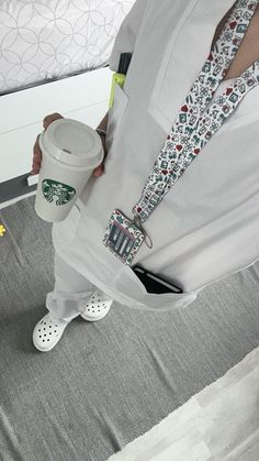 a person holding a starbucks cup in their left hand while standing on the floor next to a bed