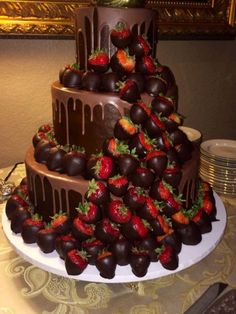 a triple layer chocolate cake with strawberries on the top and bottom, sitting on a table