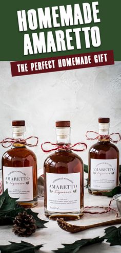 three bottles of homemade amarettoa sit on a table next to holly leaves and pine cones