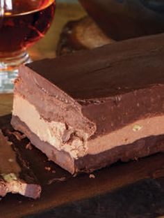 two pieces of chocolate cake sitting on top of a wooden cutting board next to a glass of wine