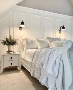 a white bed sitting in a bedroom next to two lamps on either side of it