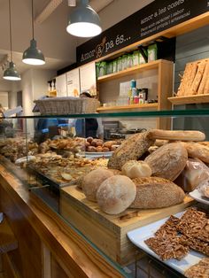 breads and pastries are on display in a bakery counter area with hanging lights