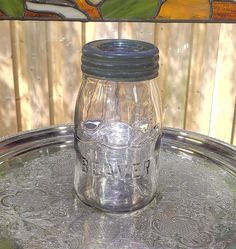 a glass jar sitting on top of a metal tray next to a stained glass window