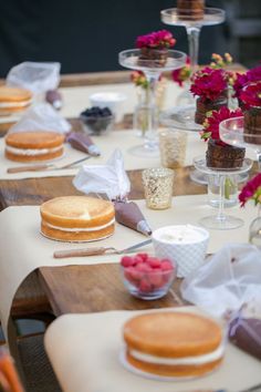 the table is set with desserts and wine glasses on it, along with flowers