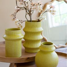 two green vases with flowers in them on a table